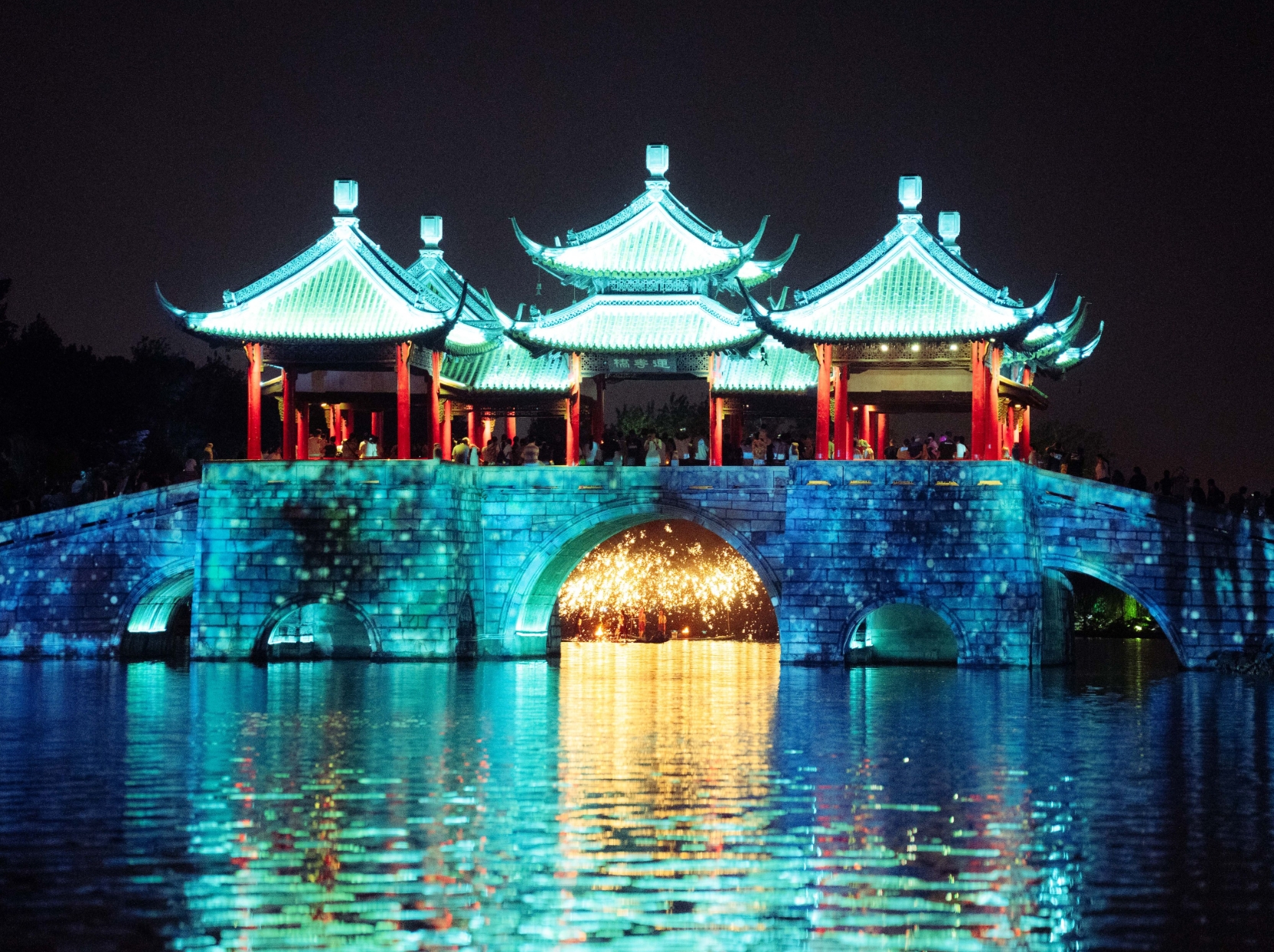 A traditional pavilion illuminated across the water