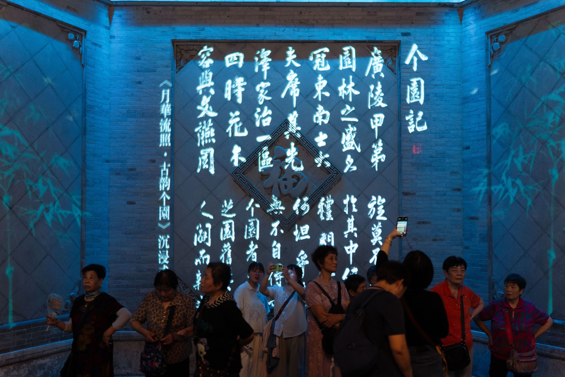 Visitors beneath illuminated classical Chinese text