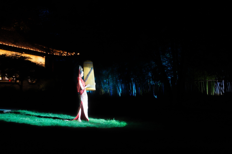 A performer standing in a narrow pool of light