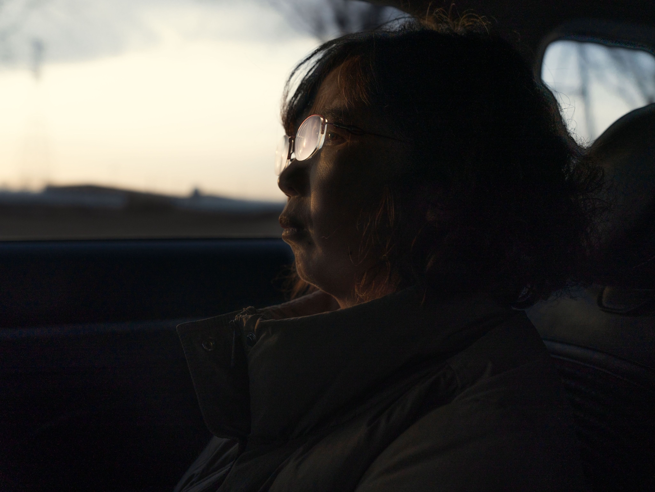 A woman sitting in a car at dawn