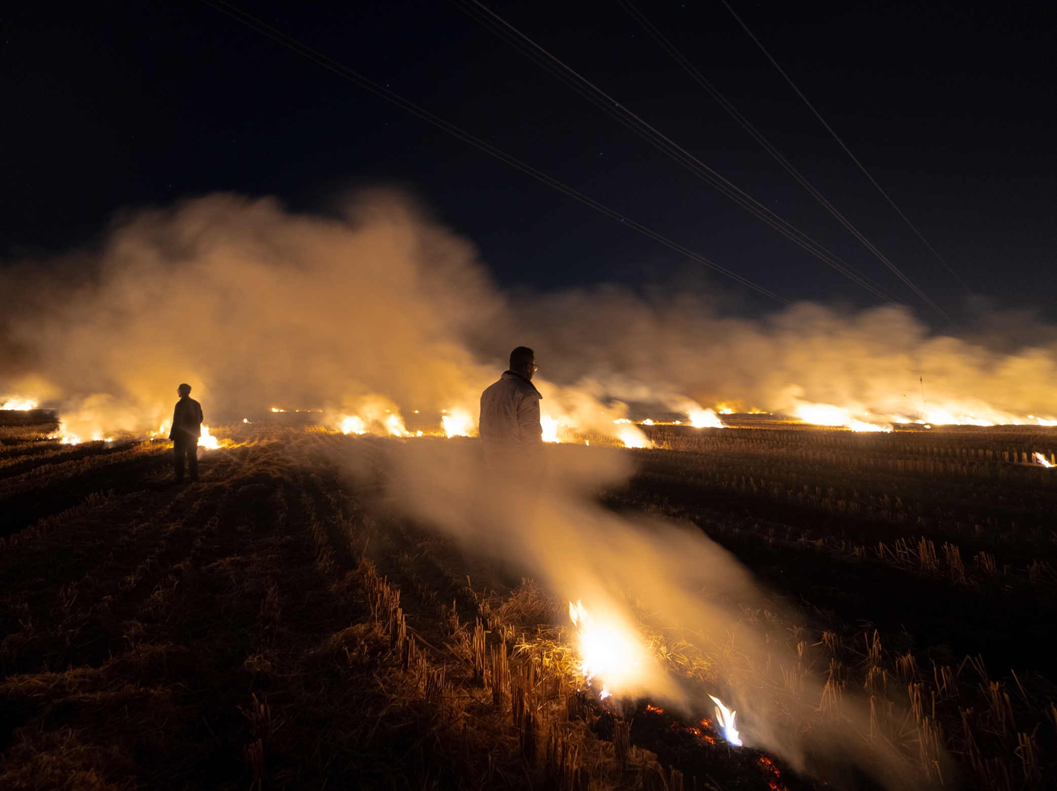 A line of fire moving across fields at night
