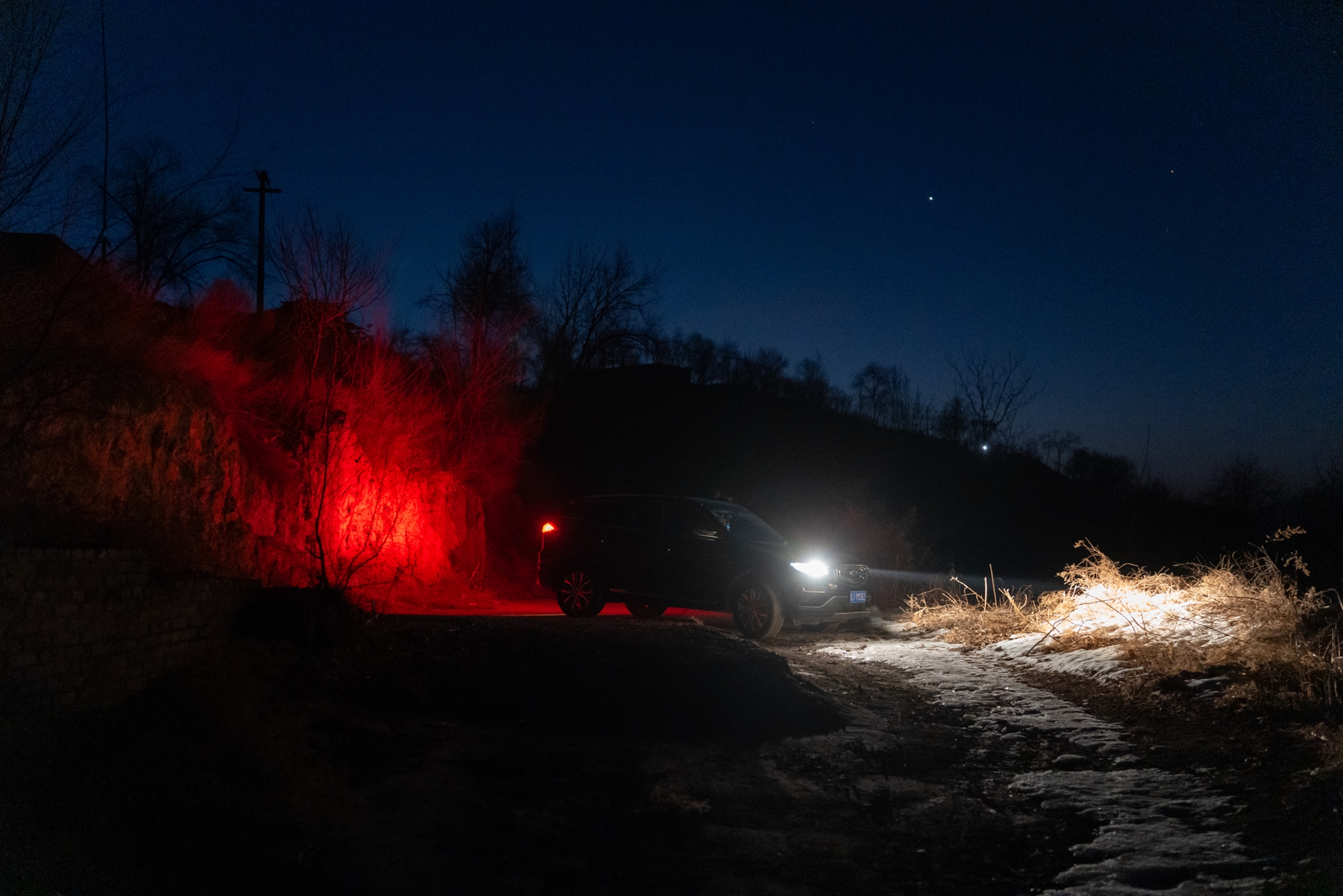 A vehicle and red light on a rural road at night