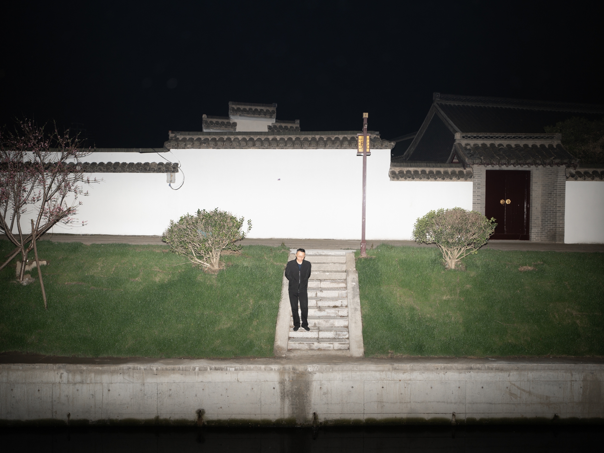 A person standing against a white exterior wall