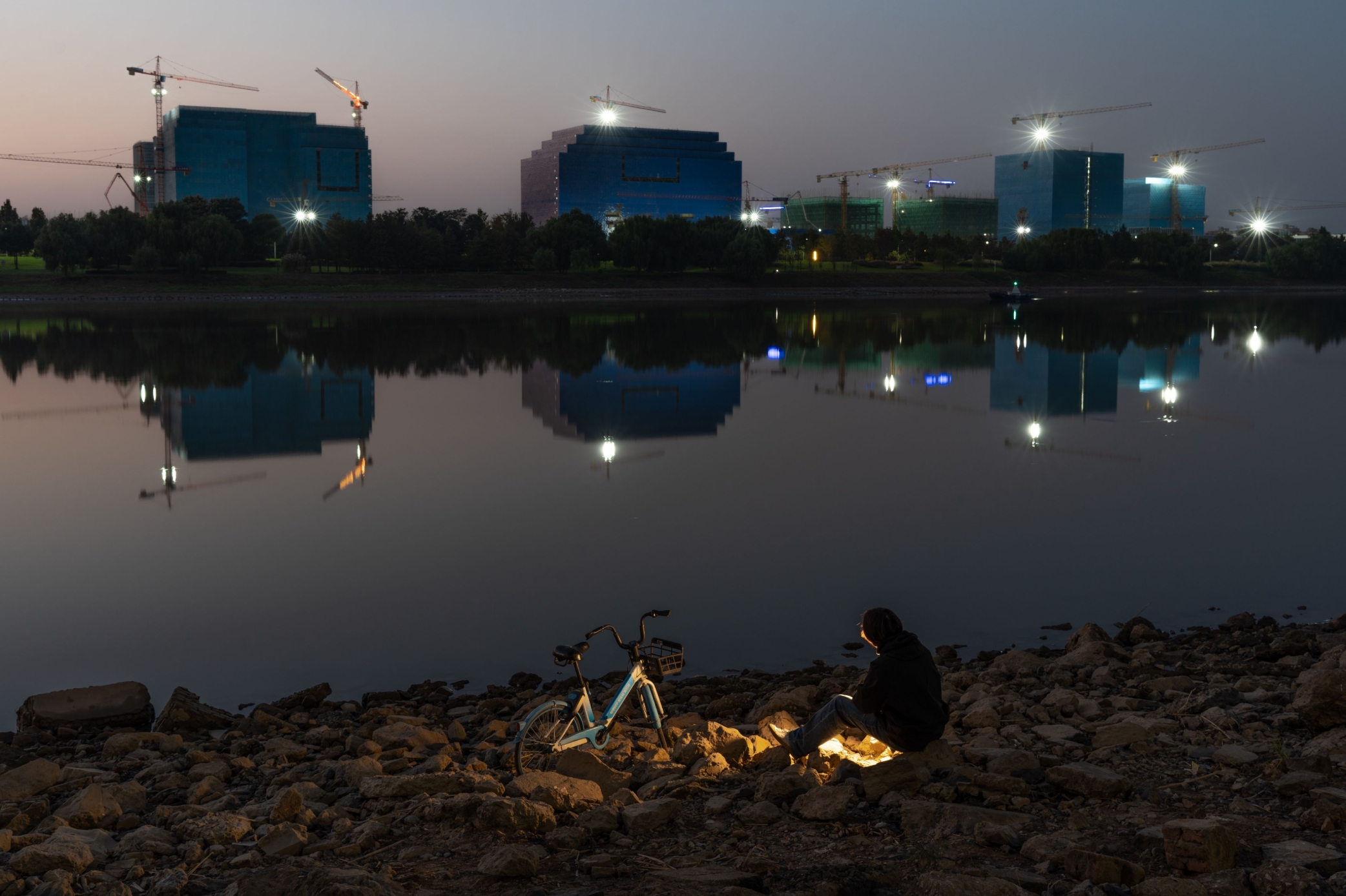 Industrial buildings reflected in a river at dusk