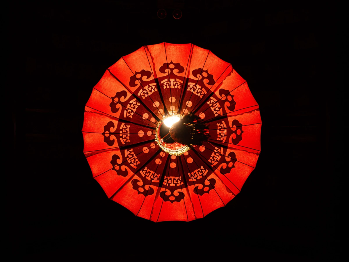 A red patterned lantern glowing against black