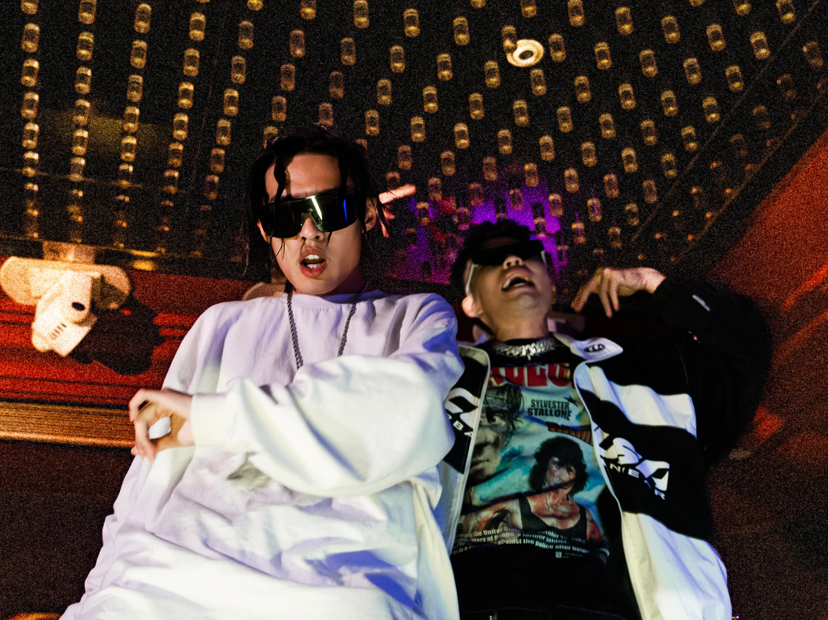 Black The Devil and GT reclining beneath a ceiling of lights