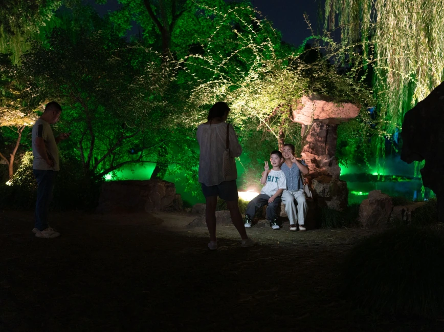 People gathered beneath green-lit trees