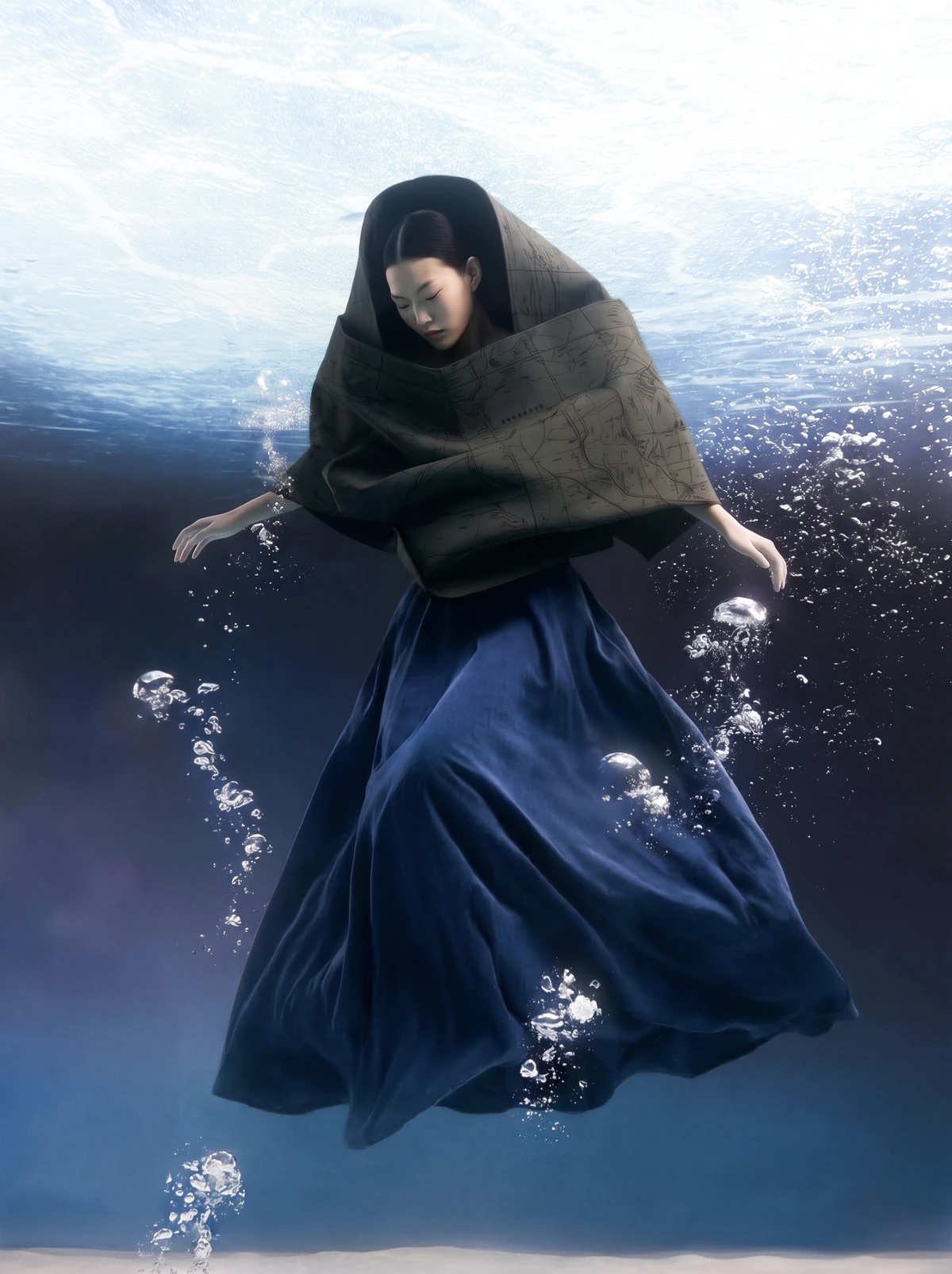 A woman in a dark sculptural garment submerged beneath water