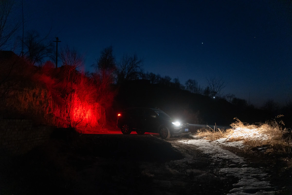 A vehicle and red light on a rural road at night