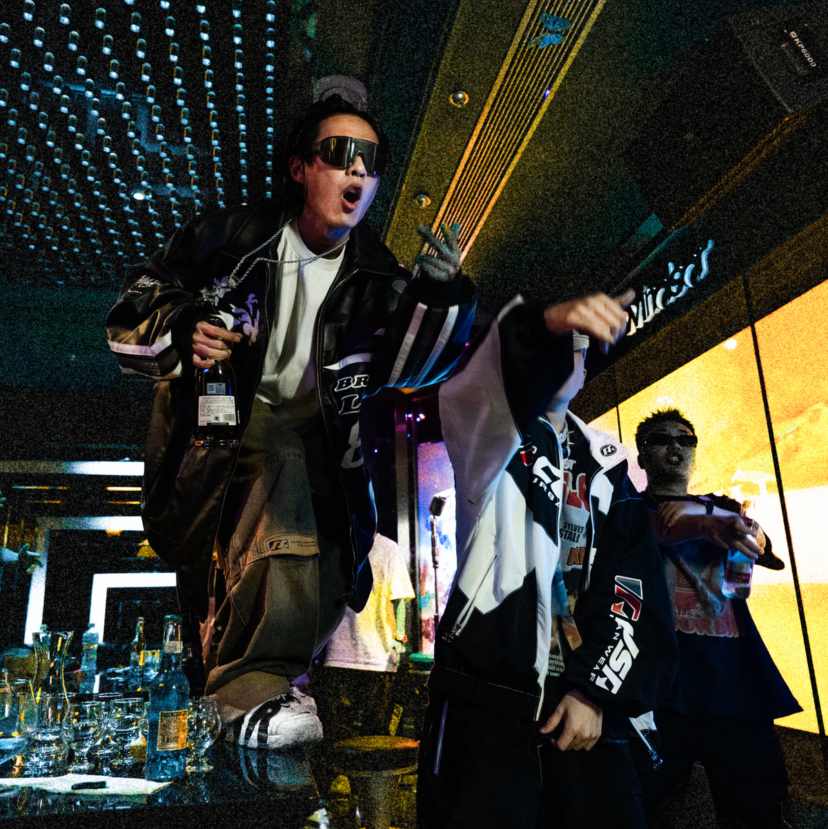 Performers in a nightclub beside a table of glasses